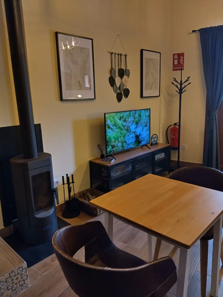 Salón con estufa y televisión en Casa Rural El Balcón del Castillo